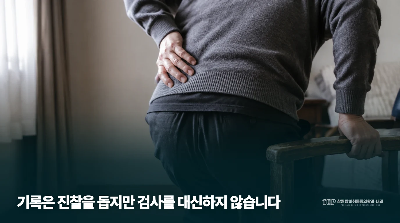 의자 팔걸이를 잡으며 허리 불편을 살피는 생활 장면